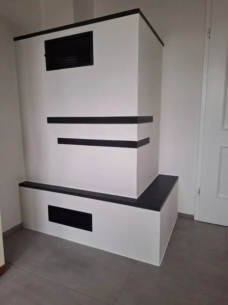 Verputzter Ofen mit schwarzem Naturstein nero assoluto Naturstein und schwarzen Gittern in Vilsbiburg