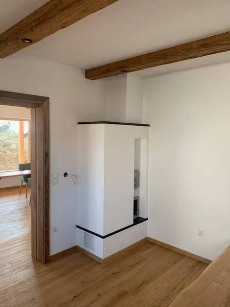 Schlichter platzsparender Ofen im Eck, verputzt und mit Naturstein nero assoluto