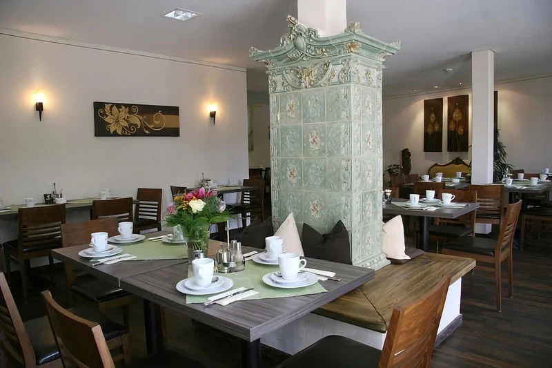 Antiker grüner Kachelofen mit Holzbank eingebaut in einem Hotel in Erding